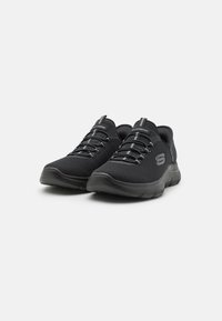 Black athletic shoes with a breathable mesh upper, elastic laces, a cushioned sole, and Skechers logo on the side.