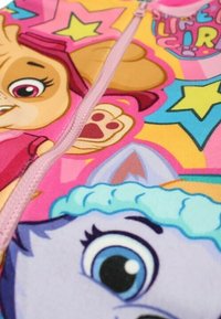 Grenouillère rose colorée avec des personnages de dessin animé, une fermeture éclair à l'avant, des motifs d'étoiles et un tissu doux. Les détails notables incluent des visages colorés et vifs.