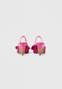 Różowe sandały na wysokim obcasie o satynowym wykończeniu, z odkrytym tyłem i ozdobną kokardą po boku. Charakteryzują się smukłymi obcasami i teksturowaną wkładką.