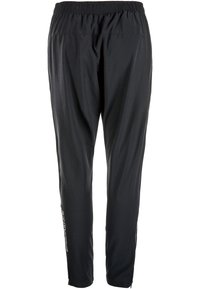 Svarta träningsbyxor med elastisk midja, tapered ben och en reflektiv logodetalj längs sidan. Slätt, lätt tyg.