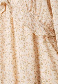 Světlé béžové látky s jemným malým růžovým a zeleným květinovým potiskem, zdobené jemným řasením na texturovaném materiálu.