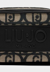 Pochette nera in pelle con cerniera, rivestita in tessuto beige strutturato caratterizzato da un motivo scuro a spirale e il logo impresso "LIU·JO MILANO".