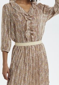 Lätt, mönstrad klänning i pastellfärger. Har en rynkad halsringning, långa ärmar och en insvängd midja med ett krämfärgat bälte.