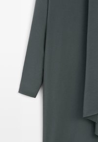 Abbigliamento a maniche lunghe in un tessuto morbido di color grigio scuro. Presenta una forma rilassata con una texture liscia e maniche a taglio dritto.