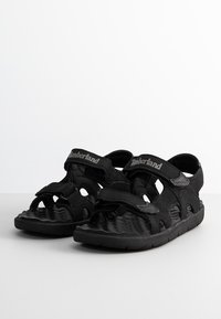 Sandalias negras con múltiples correas, cierres de Velcro y una suela texturizada. Fabricadas con material sintético y un diseño ligero.