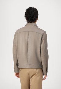 Jaqueta de couro cinza claro com colarinho, apresentando uma textura suave e costuras mínimas. Design ajustado, terminando na cintura.