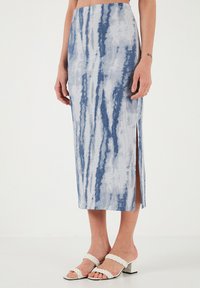 Modrá a bílá midi sukně s technikou tie-dye, rovného střihu, se bočním rozparkem a texturovanou tkaninou. V kombinaci s bílými sandály se splétanými popruhy.