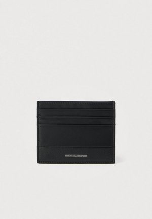 Czarny skórzany wizytownik z wieloma przegródkami, o gładkiej fakturze i srebrnej plakietce z logo. Kompaktowy, prostokątny kształt.