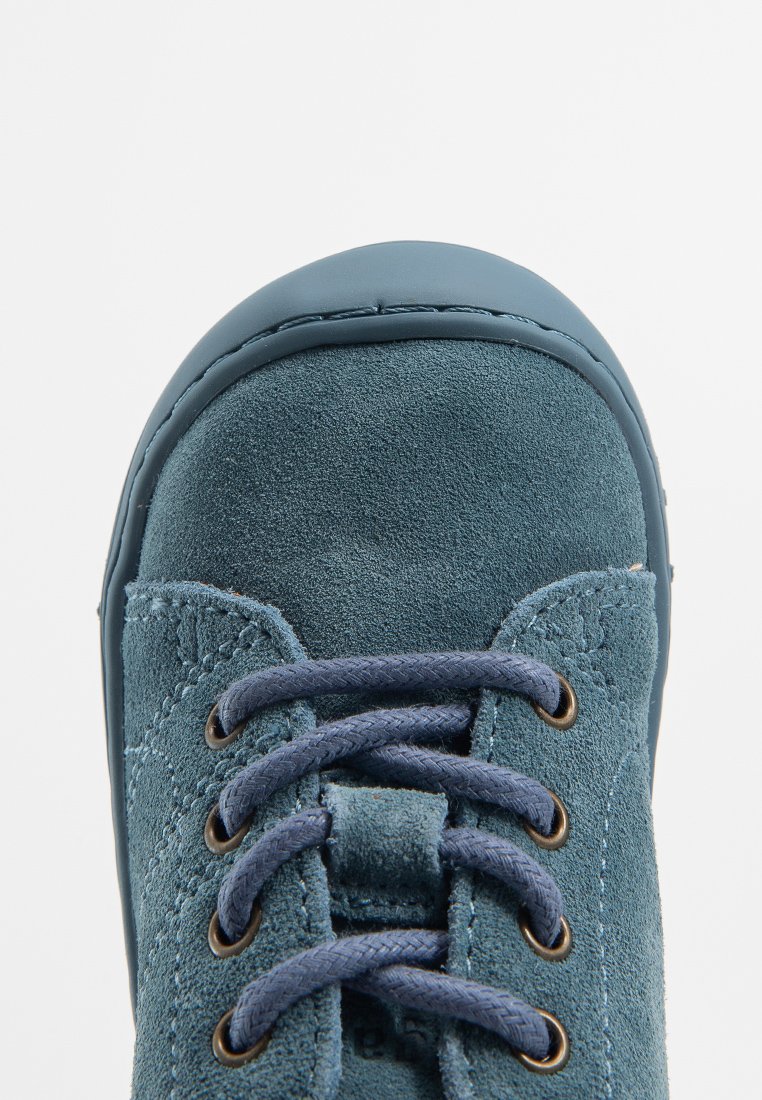Türkisfarbene Wildleder-Sneaker mit abgerundeter Spitze, marineblauen Schnürsenkeln und bronzefarbenen Ösen. Verfügt über eine strukturierte Oberfläche und eine Gummisohle.