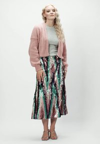 Różowy sweter z dzianiny, srebrny top ze ribbingu oraz spódnica z wielokolorowymi cekinami w zygzaki w odcieniach zieleni, różu i fioletu. Srebrne sandały.