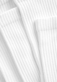 Chaussettes en coton blanc avec une texture côtelée, présentant plusieurs couches repliées les unes sur les autres, mettant en avant des rayures horizontales.