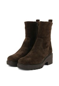 Stivaletti in suede marrone con suola piatta spessa, chiusura con zip sul lato e alette superiori per una facile calzata.