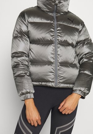 Skinnende grå dunjakke med hætte og lynlås båret over sorte leggings med grå geometriske mønstre.