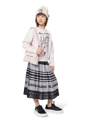 Light pink sweatshirt with graphic print, gray pleated skirt with logo pattern, black sneakers with white sole, and beige beanie hat.
