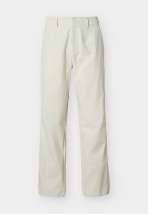 Bež hlače naravnost krojene z zankami za pas, stranskimi žepi in zadrgo na sprednji strani, prikazane na belem ozadju.