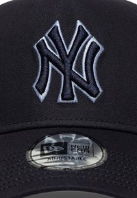 Μαύρο καπέλο μπέιζμπολ από ύφασμα, με κεντημένο γκρι λογότυπο των New York Yankees. Ρυθμιζόμενο πίσω μέρος με στρογγυλή αυτοκόλλητη ετικέτα New Era στο εσωτερικό.
