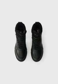 Svarta läderkängor med en texturerad svart fleecekrage, rund tå och snörningsdesign. Hållbar sula för grepp och stöd.