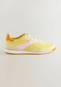 Sneaker giallo con dettagli rosa e arancione, caratterizzato da una tomaia in pelle liscia e suede, lacci bianchi e una suola in gomma texturizzata.