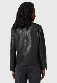 Black leather jacket with a smooth texture, featuring a fitted design, zippered cuffs, and a clean, minimalist cut.