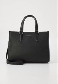 Borsa a mano in pelle nera con finitura testurizzata, doppi manici, tracolla regolabile e dettagli in metallo argentato. Presenta il logo Lacoste sul davanti.