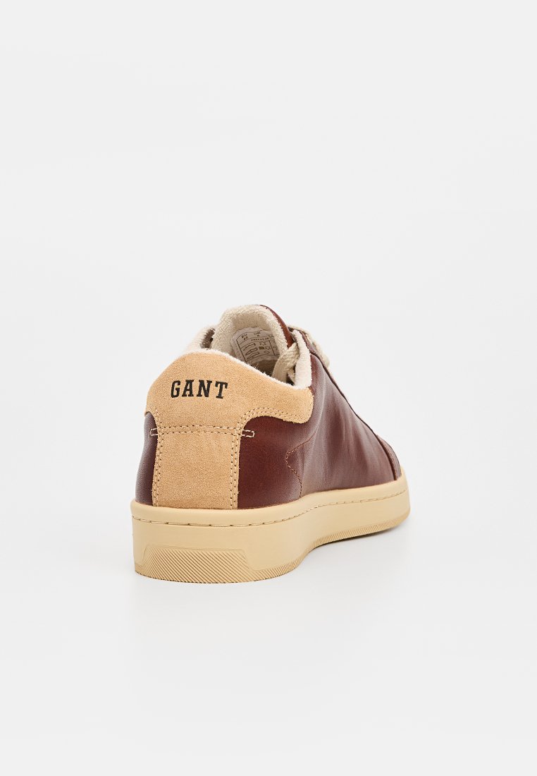 Brązowe skórzane trampki z beżowym zamszowym piętkiem i gumową podeszwą, z czarnym logo "GANT" na pięcie. Czysty, minimalistyczny design.