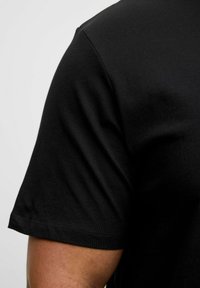 Sort kortærmet t-shirt lavet af glat bomuld med rund hals. Klare syninger langs kanten og ærmeenderne, samt tætsiddende design.