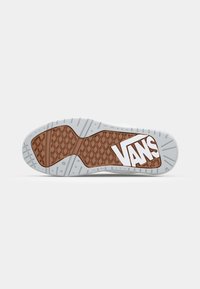 Semelle en caoutchouc marron avec un motif texturé, arborant le logo Vans blanc. Murs latéraux blancs, design de semelle plate pour une adhérence et une durabilité optimales.