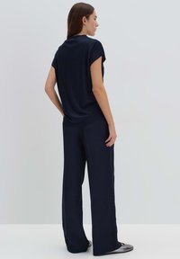 Top blu navy a maniche corte abbinato a pantaloni larghi e comodi. Tessuto morbido con una texture liscia e un design minimale.