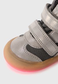Gray fabric sneaker with mesh accents, featuring two velcro straps, a rounded toe, and a translucent sole with a pink glow effect.