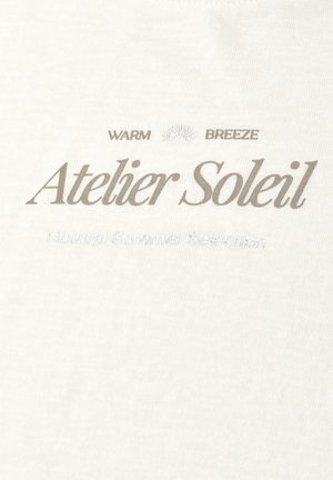 Mærkenavnet "Atelier Soleil" i stor skrift med mindre tekst "WARM BREEZE" og svag "Natural Summer Selection" på lys stofbaggrund.