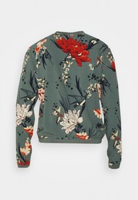 Zielona bluza z długim rękawem, w czerwono-białe wzory kwiatowe i ptasie, z elastycznymi mankietami i dołem, pokazana z tyłu.