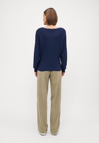 Navy geribbelde trui met een brede hals en lange mouwen, gecombineerd met losse, lichtbeige corduroy broek.