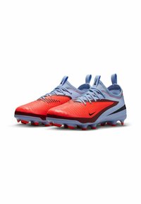 Des chaussures de football rouges et bleues présentent une surface texturée, des accents noirs, des pointes en caoutchouc et des languettes pour un enfilage facile. Conçues pour la performance.