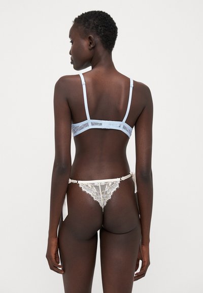 Reggiseno in pizzo blu chiaro con spalline regolabili e chiusura a gancio. Perizoma in pizzo crema abbinato con lacci. Motivi in pizzo dettagliati in tutto.