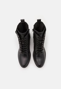 Bottines en cuir noir avec lacets à l'avant. Comprennent un bout rond, une fermeture éclair latérale et des accents texturés.