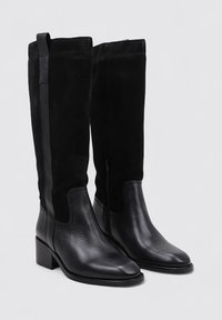 Botas negras hasta la rodilla que presentan una combinación de cuero liso y ante, puntera cuadrada, tacón de bloque y cremallera lateral para un acceso fácil.