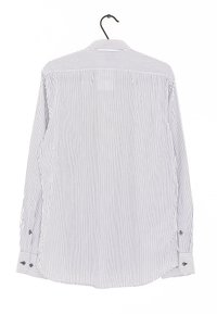 Camisa de botones a rayas en blanco y azul marino, de manga larga, con puños de doble botón y cuello clásico, colgada de un gancho.