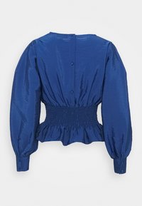 Blusa blu con texture, caratterizzata da maniche a sbuffo, vita arricciata e chiusura a bottoni sul retro. Tessuto liscio con leggero lucido.