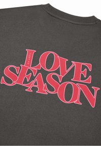 Šedá mikina s výrazným červeným nápisem "LOVE SEASON" a menším textem "OH APRIL", uspořádanými v dynamickém rozložení.