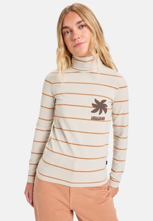Kremfarget turtleneck med horisontale brune striper, med en brun grafisk logo på brystet. Myk, elastisk stoff.