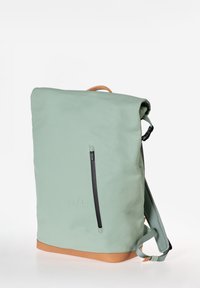 Zaino impermeabile verde con chiusura roll-top, dotato di una tasca frontale con zip, base in pelle marrone e spallacci imbottiti.