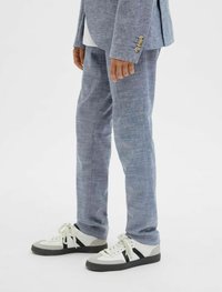 Világoskék, textúrált len öltöny, slim fit nadrággal. Fehér sportcipővel párosítva, szürke és fekete részletekkel.