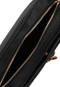 Clutch in pelle nera con superficie texturizzata, dotata di chiusura con zip dorata e scomparto interno, che mette in evidenza dettagli di cucitura intricati.