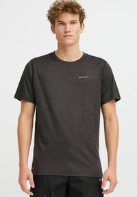 Camiseta de manga corta y cuello redondo en tela de color gris oscuro con textura sutil; presenta un pequeño logo blanco en el lado izquierdo del pecho.