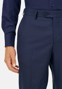 Pantalones marinos de rayas diplomáticas con una textura suave, que cuentan con cierre de botón y pasadores para cinturón, además de una silueta ajustada.