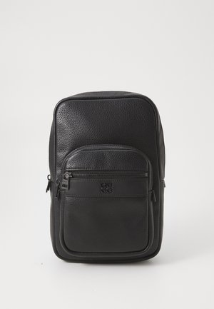 Zaino in pelle nera con finitura testurizzata, tasca frontale con zip e dettaglio del logo. Forma rettangolare, schienale imbottito e zip robuste.