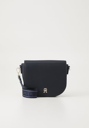 Borsa a tracolla in pelle blu navy con patella curva, finiture dorate e tracolla con logo su un nastro intrecciato.