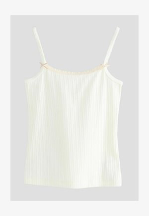 Baltas grublėtas cami viršus su plonomis petnešėlėmis, turintis subtilų nėriniuotą apvadą ir mažą rožinį kaspinėlį prie kaklo. Minkštas tekstūras.