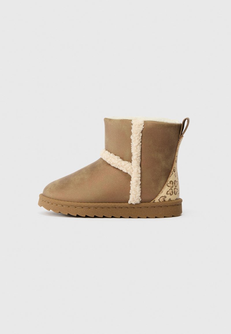 Bota castanha até ao tornozelo com um acabamento suave e texturizado. Apresenta detalhes em pelagem creme, um salto padronizado e uma sola de borracha com textura em zigzag.