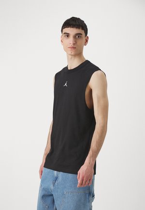 Crna pamučna majica bez rukava s bijelim Air Jordan logom na prsima. Majica ima opušteni kroj i okrugli izrez.